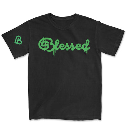 Black t-shirt featuring "Blessed" in a vibrant green script font with a dollar sign ($) replacing the 'S' and a green drip effect on the lettering. A green stylized 'B' logo is on the left sleeve.