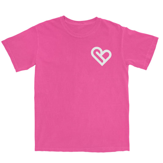 A bright pink t-shirt with a white PSTVE (Positive) Brand logo on the left chest is displayed against a white background. The t-shirt has short sleeves and a round neckline.
