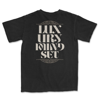 Back of a black t-shirt with large, ornate beige text that reads "LUXURY MINDSET." The text is framed by decorative, swirling line art above and below it.